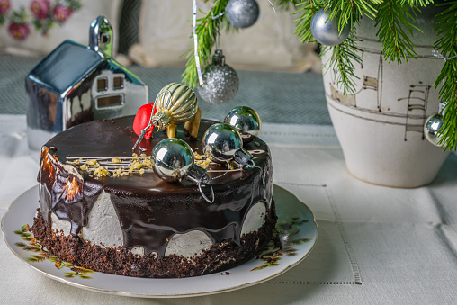New Year's cake drizzled with chocolate on a table with fir branches.