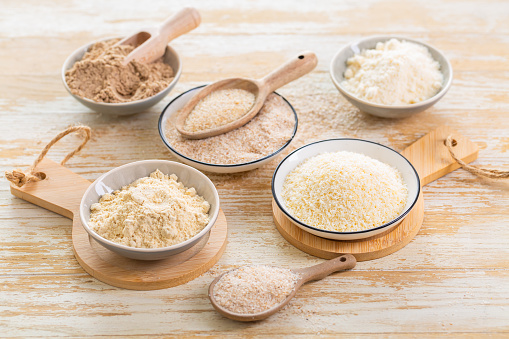 Buckwheat flour in a bowl and buckwheat grain in a spoon close up