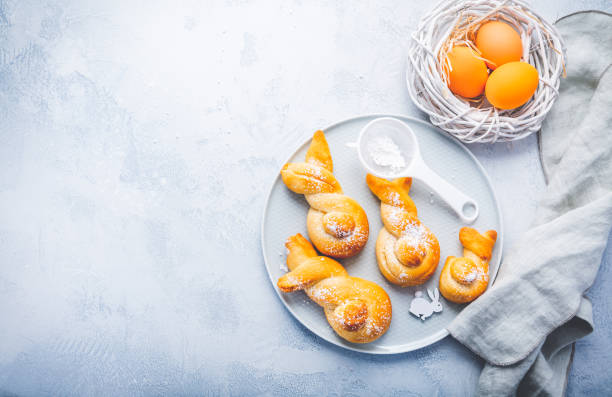 istock Buns made from yeast dough in a shape of Easter bunny and colored eggs 2022063884