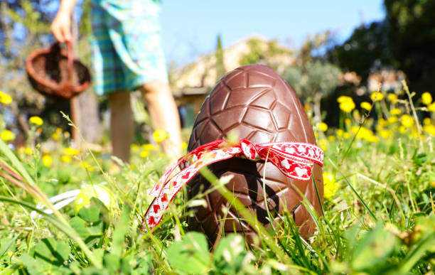 Huevo de Pascua en hierba verde con el niño sosteniendo la cesta de mimbre - foto de stock