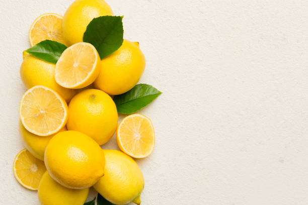 istock Many fresh ripe lemons with green leaves on colored background, top view, space for text 2022085572