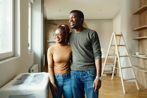 Happy African American couple looking through window after moving into a new apartment.