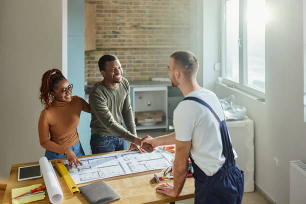 istock Happy black couple shaking hands with manual worker in moving house. 2022100471