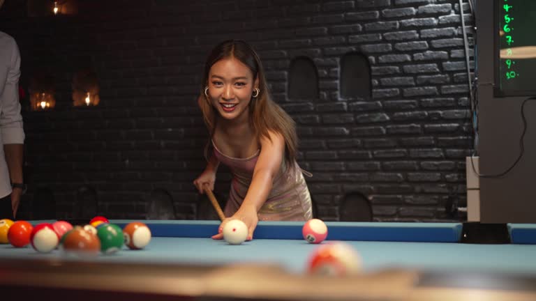 People play billiards at night club.