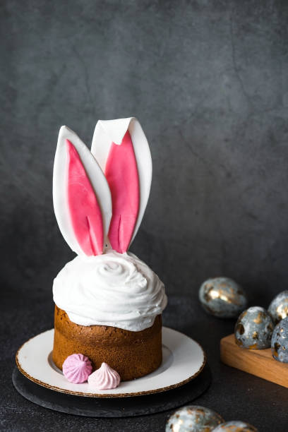 istock Beautiful stylish still life. Easter cake with rabbit ears, meringue, marshmallows, Easter eggs and willow twigs on a dark background. happy Easter 2024. 2022122796