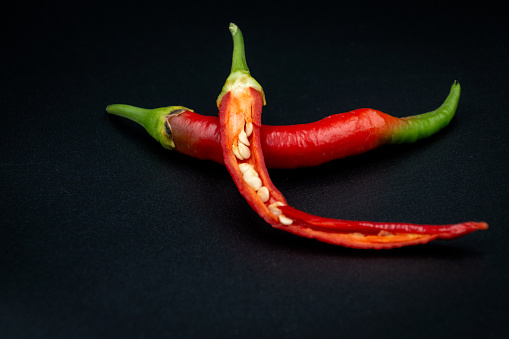Two vibrant red chili peppers placed on a sleek black backgroundh