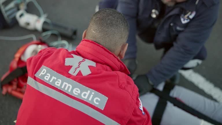 Paramedic, team and man with first aid in emergency, care or helping with injury, accident or medical crisis. EMT, service and people in healthcare, save a life or rescue woman in car crash or danger