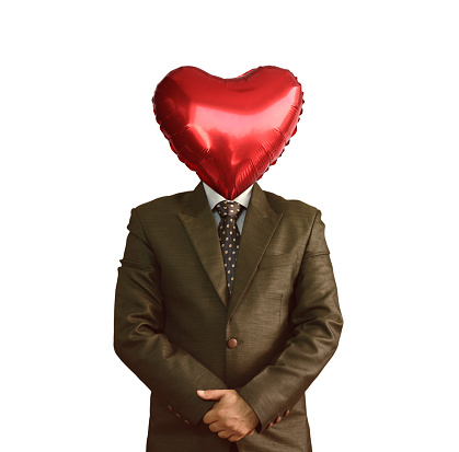 Whole heartedly- Cutout of waist up unrecognizable suited man in shirt, necktie, gray blazer, face replaced by heart shape solid shiny balloon standing with hands clasped isolated over white background. Apt for I love you theme Valentine Day romantic wedding or marriage proposal backdrops,  and posters templates