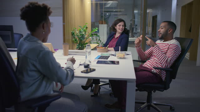Man talking to his two female coworkers during a lunch break in the office