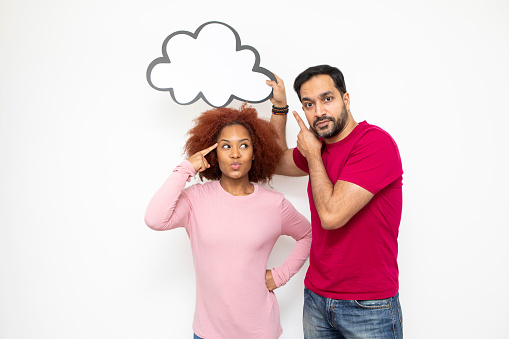 Couples with ideas and making decisions concept: Mid-adult man holding a blank cloud bubble for your message above a young woman. They are both pointing.