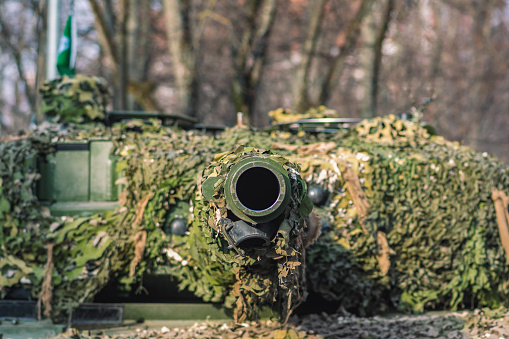 Machine gun breast ring magazine pouch with bulletproof vest and steel helmet lying on a camouflage net of a tank.