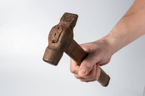 A close-up of an iron hammer in a worker's hand stock photo