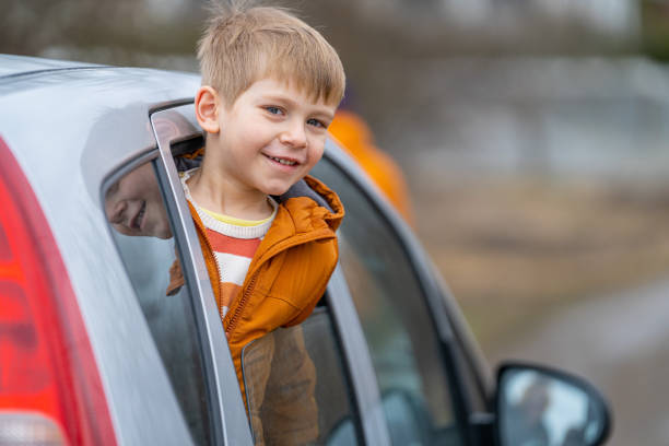istock Smiling little boy peeping outside car 2022218368