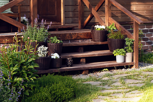 wooden rustic country house front porch decorated with rattan flower pots. Summer life.