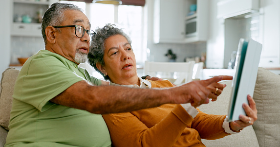 Old couple, tablet and home teaching or online bingo in living room or explain internet or connectivity, social or scroll. Man, woman and web scrabble on sofa in Mexico or retirement, app or marriage