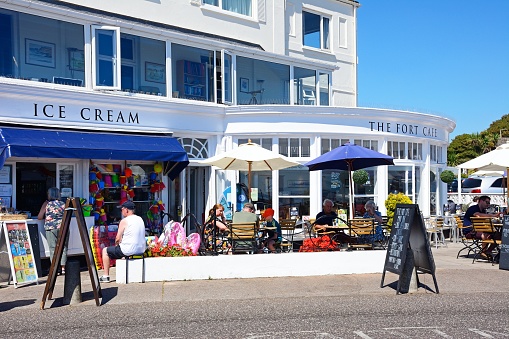 Tourists relaxing outside the Fort Cafe along the promenade, Sidmouth, Devon, UK, Europe.