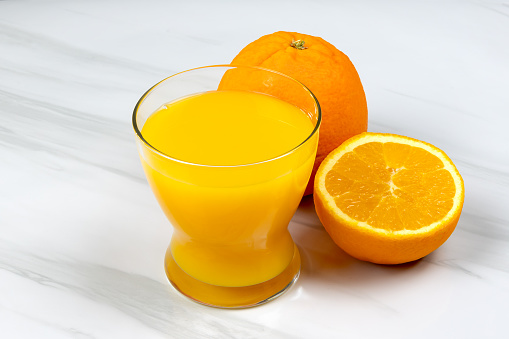 Picture of organic orange juice beside fresh oranges.