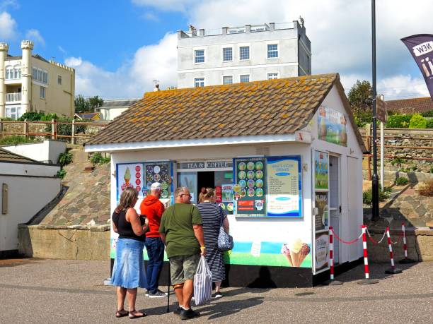 Tourists queuing at an ice cream kiosk along the promenade, Seaton, Devon, UK, Europe.
