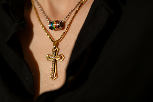 Lesbian woman wearing Catholic cross and LGBTQ rainbow necklace