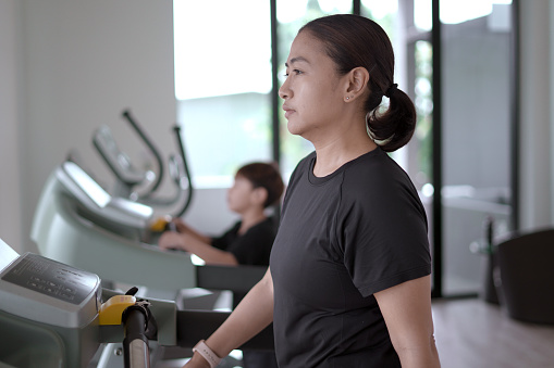 Woman and a boy run on a treadmill, exercising.