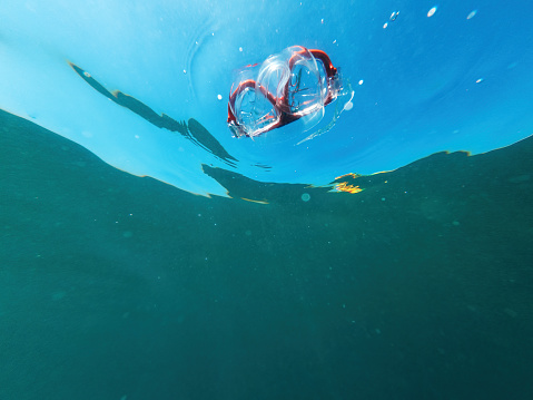 Underwater shot of snorkeling mask floating in ocean water, selective focus