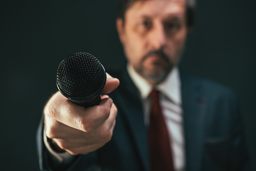 Journalist pointing microphone towards the view during interview, first person pov, selective focus