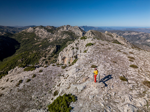 A woman standing on a rocky point overlooking Mediterranean sea, Malla del Llop peak, Alicante, Costa Blanca, Spain - stock photo