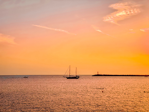Beautiful sunset over the sea with a sailboat in the foreground
