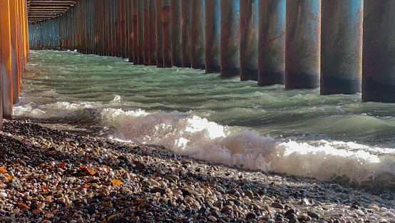 A closeup shot of a beach under a bridge with pebbles