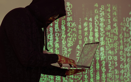 Side view on hacker in black hoody with laptop at binary code digital background. Be aware of hacker attack.