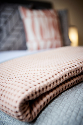 Blanket, fabric and interior of hotel bed with duvet, comforter and pillows for accommodation. Closeup of empty bedroom, house or apartment at resort with soft cushion, material or linen at home