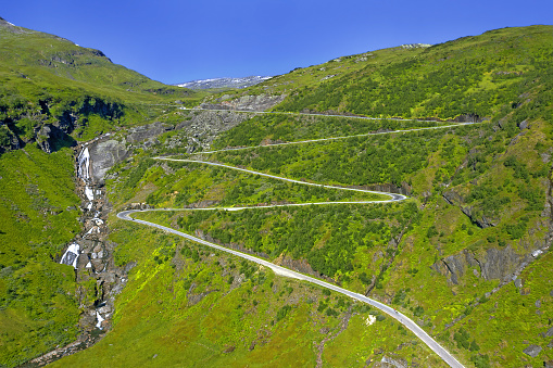 Norway serpentine mountain road on hill distance view with waterfall. Scandinavia, Myrkdalsvegen road, Serpentinveg, Sendefossen