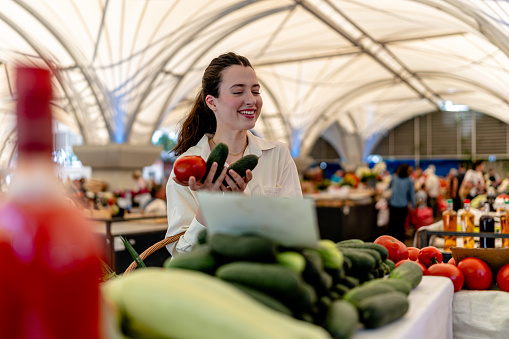 Immersed in the vibrant atmosphere of the street market, the woman carefully selects an array of fresh and flavorful vegetables, savoring the connection to local growers and embracing the goodness of farm-to-table produce