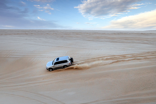 Doha, Qatar - February 16, 2024: A Toyota Land Cruiser climbing up the desert mountain in Sealine Sand Dunes, Mesaieed, Qatar.