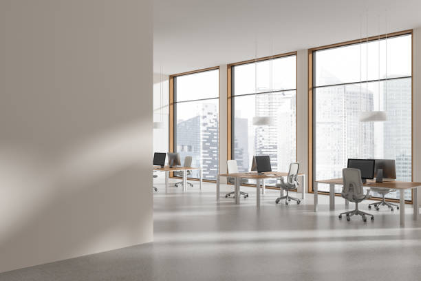 istock Stylish coworking interior with pc desktop and table near window. Mock up wall 2022398445