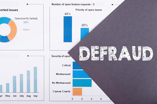 The word DEFRAUD is written on a gray background with diagrams and graphs.