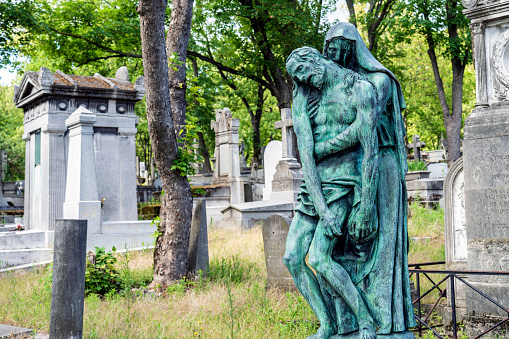 Close up view of  Parisian graveyard with bronze statue and tombs in France