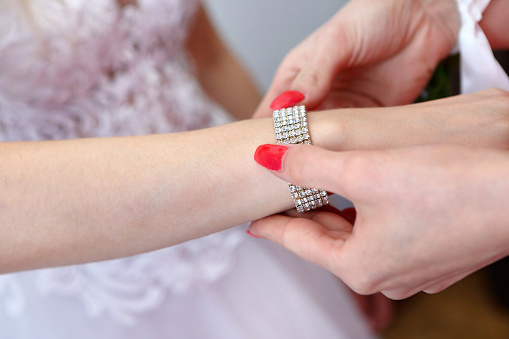 Diamond bracelet put on the bride's hand by mom and empty space for text