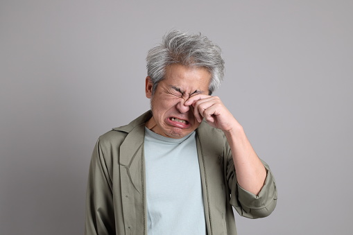 The 40s Asian man with smart casual clothes standing on the grey background.