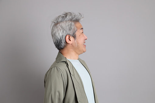 The 40s Asian man with smart casual clothes standing on the grey background.