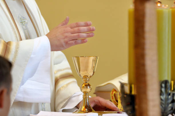 istock Chalice on the altar and priest celebrating mass in the background 2022409480