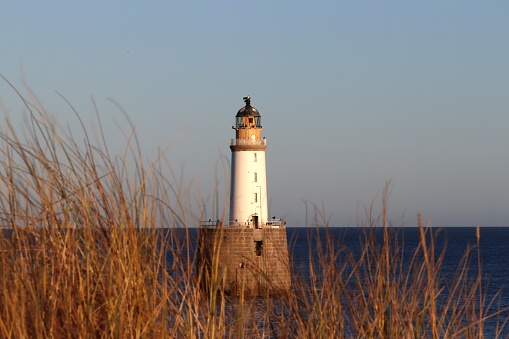 The black-and-white striped Big Sable Point Lighthouse (1867) and lots of gulls at the beach in early summer;  the lighthouse in the Ludington state park is one of Michigan's most beautiful; water, sand and sky in soft evening colors 