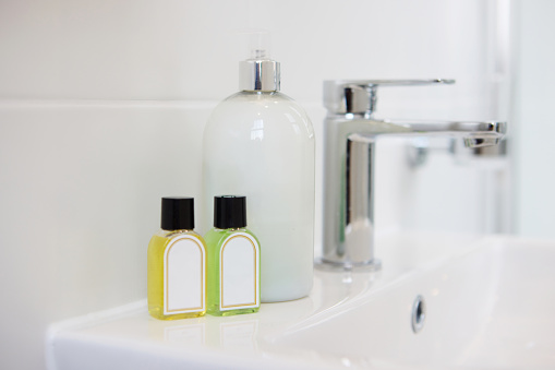 Bathroom, soap and dispenser at hotel for hygiene, accommodation or cleaning equipment at resort. Closeup of interior, sink or tap with containers, bottle or domestic decor of toiletries at home