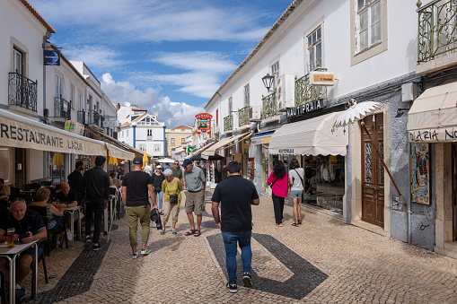 Lagos, Algarve, Portugal - October 21, 2023: People in lively Old Town with restaurants and shops along cobbled pedestrian street.