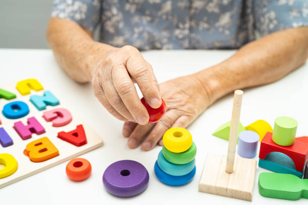istock Alzheimer disease AD, Asian elderly woman patient suffering from dementia learn practical motor skills rehabilitation. 2022440011