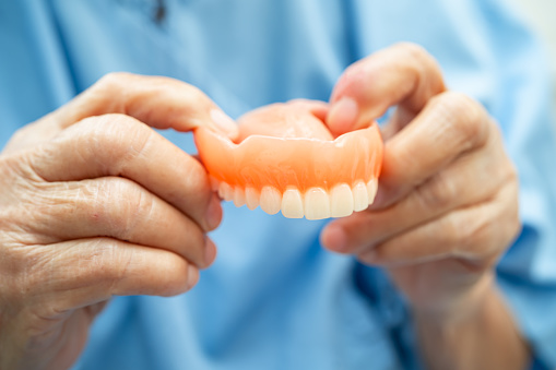 Asian elderly woman patient holding to use denture, healthy strong medical.