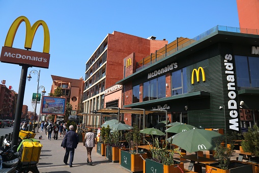 People walk by McDonald's fast food restaurant in Morocco. McDonald's is one of largest global fast food chains.