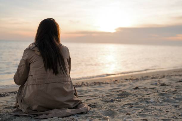 istock Lovely woman sitting on the beach 2022444454