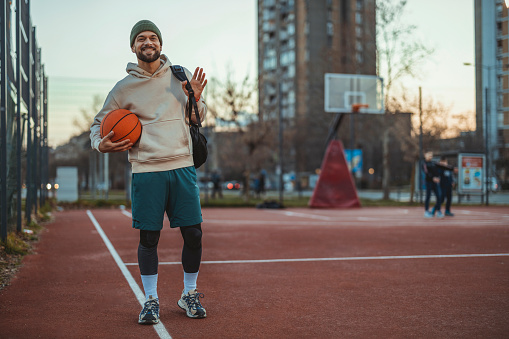 Portrait of Handsome Male Basketball Player Posing With a Basketball on the Court at Dusk. Sport, Active Lifestyle Concept.