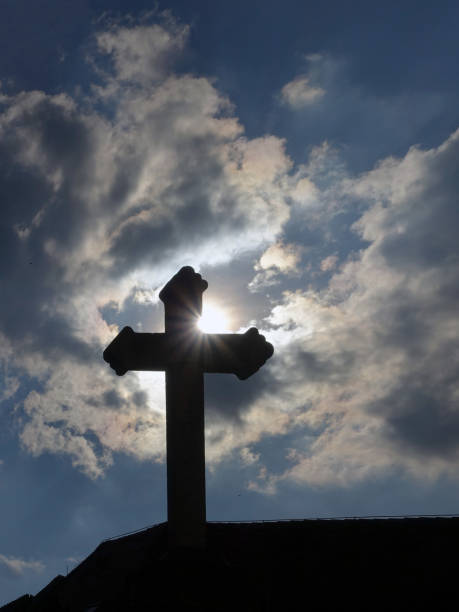 istock Backlit church cross on roof with sun rays 2022457200